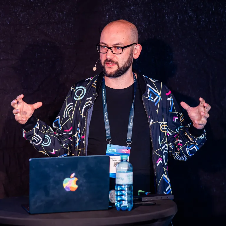 Darius Erdt bei einem Vortrag beim OMT Agency Day, gestikulierend hinter einem Stehtisch mit Laptop